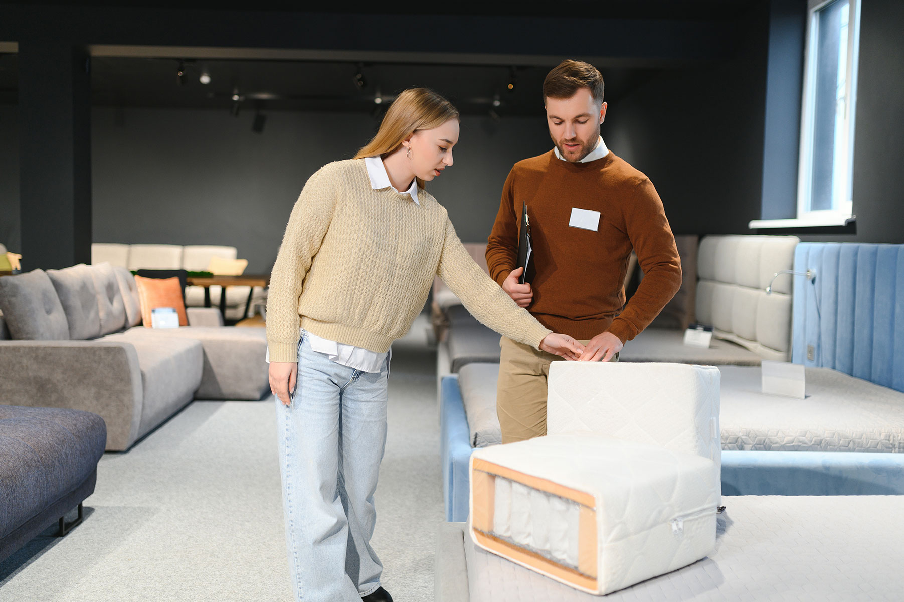 salesman-explaining-to-woman-customer-at-furniture-2024-04-16-17-54-27-utc