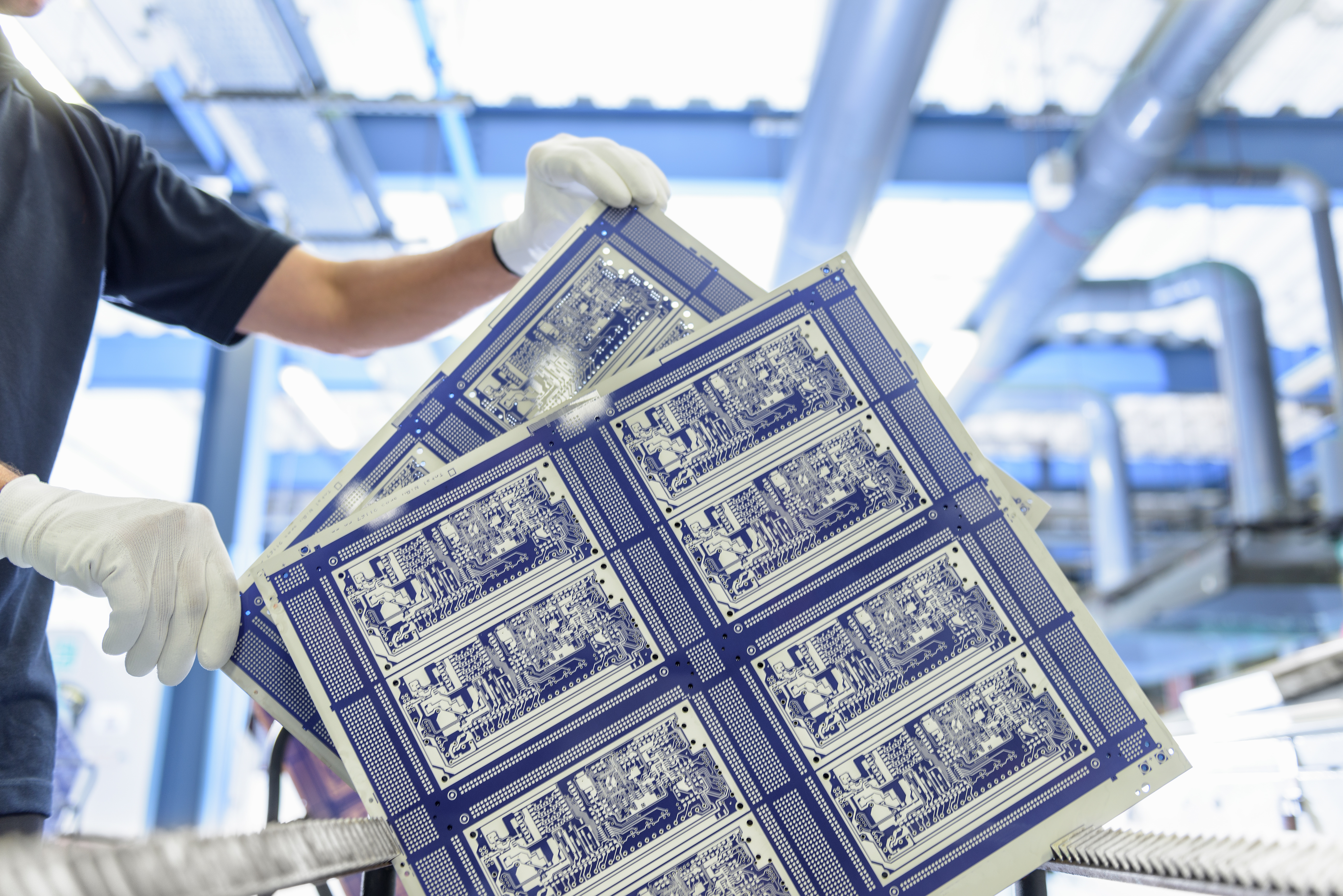 Worker inspecting circuit board in circuit board factory